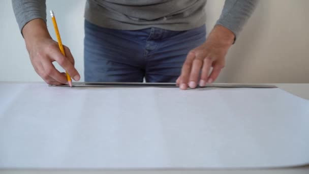 Primer plano manos masculinas preparando nuevo rollo de papel pintado y marcado con lápiz y regla en la mesa de interior — Vídeos de Stock