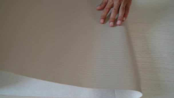 Primer plano manos masculinas preparando nuevo rollo de papel pintado flexión en la mesa interior — Vídeos de Stock