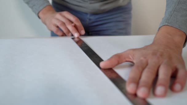 Primer plano manos masculinas preparando nuevo rollo de papel pintado y marcado con lápiz y regla en la mesa de interior — Vídeos de Stock