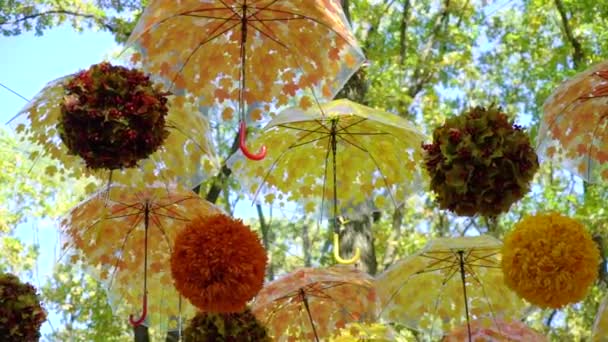 Un sacco di ombrelloni e palline luminosamente arancioni e gialli appesi e in movimento al vento nel parco autunnale . — Video Stock
