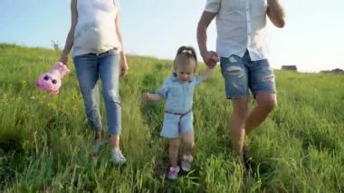 Hamile çift el ele tutuşarak doğada yürüyüş yürümeye başlayan çocuk kızı ile