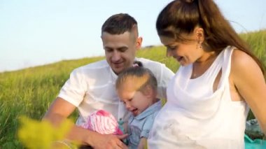 Closeup hamile çift yürümeye başlayan çocuk kızı ile boş zaman açık havada battaniye çim sahada var