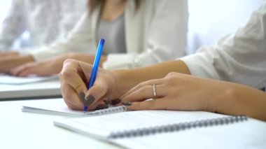 Genç erkek ve dişi öğrenci eller sınıf içinde defter kalem ile yazma