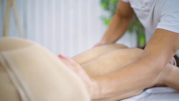 Mannelijke masseur handen masseren mooie jonge vrouw terug op tafel in spa centrum. — Stockvideo