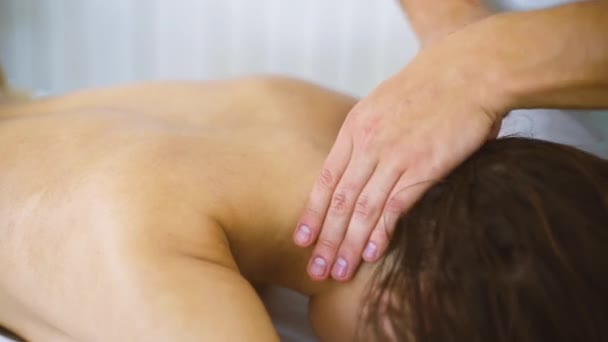 Mannelijke masseur masseren van de nek van de mooie jonge vrouw op tafel in spa center closeup. — Stockvideo