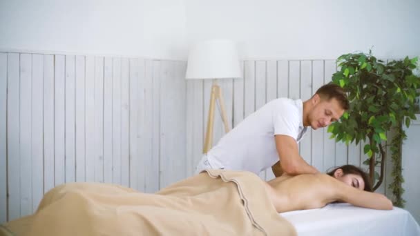 Massagista masculino massageando bela jovem de volta à mesa no centro de spa . — Vídeo de Stock
