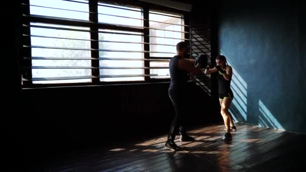 Silhouette einer fitten weißen Boxerin beim Training mit einem Boxtrainer im Fitnessstudio. — Stockvideo