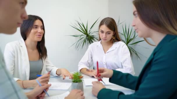 Grupo de estudiantes de secundaria discutiendo y resolviendo la asignación de proyectos en la mesa juntos — Vídeo de stock