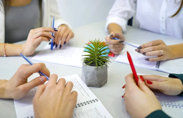 kalem ve defter üzerinde tablo ile erkek ve dişi öğrenci eller