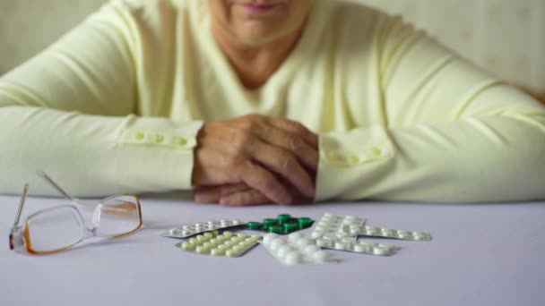 Senior vrouw handen met pillen en brillen op tafel thuis closeup — Stockvideo