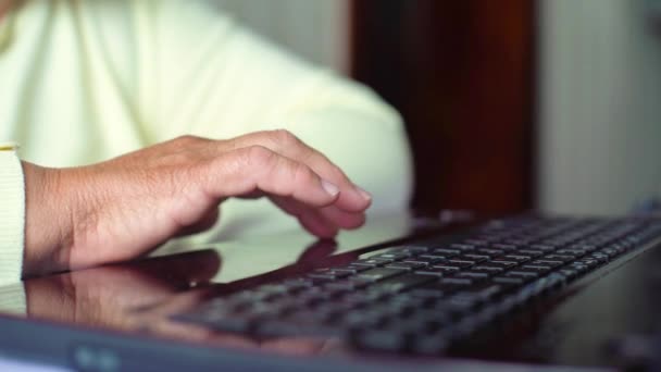 Крупный план пожилая женщина рука на ноутбуке клавиатуры серфинг интернет дома с бесплатным и копировать пространство — стоковое видео