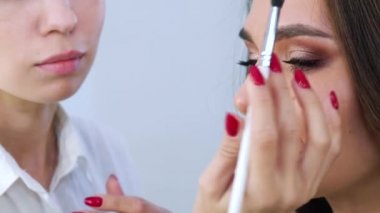 güzel kadın yüz fırça güzellik salonu closeup ile kozmetik uygulayarak kadın makyaj sanatçısı