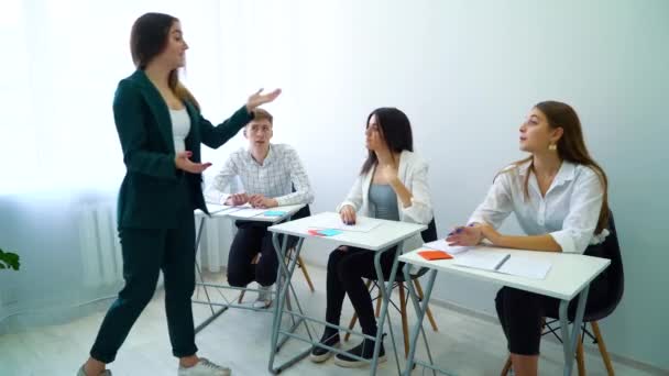 Jovem professor ajudando e explicando os alunos em sala de aula — Vídeo de Stock