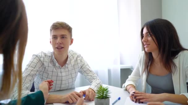 Középiskolás diák csoport megvitatása és megoldása projekt-hozzárendeléskor asztalnál együtt — Stock videók