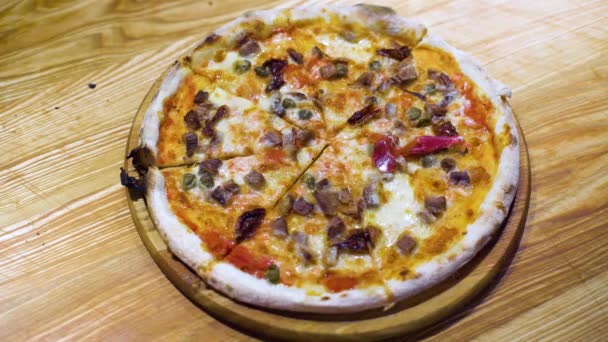 Свежая запечённая пицца, разрезанная на ломтики, украшенные ломтиками ветчины, сливочным сыром, растительным маслом — стоковое видео