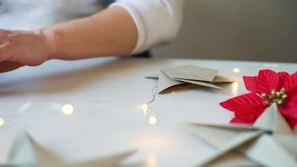 Pan tiro de mãos de mulher dobrando origami estrela de papel para decoração de Natal — Vídeo de Stock