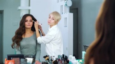 Genç kadın yüz Güzellik Salonu toz uygulayarak makyaj sanatçısı ayna yansıması