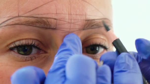 Schoonheidsspecialiste tekeningshape nieuwe wenkbrauw voor microblading op vrouwelijke gezicht close-up — Stockvideo