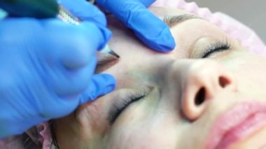 Genç kadın yüz kaş microblading güzellik salonunda getting closeup