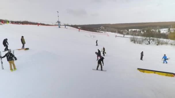 Luchtfoto van snowboarders glijdend van besneeuwde helling en rijden omhoog met skilift — Stockvideo