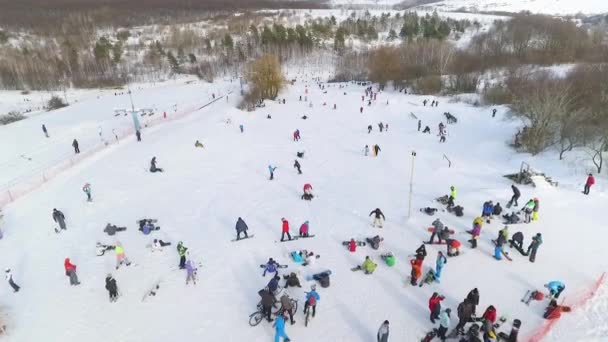 Aerea di sciatori e snowboarder che scivolano lungo pendii innevati e risalgono con gli impianti di risalita — Video Stock