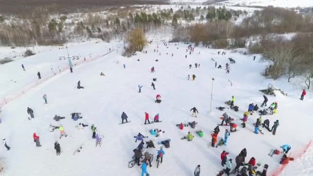 Αεροφωτογραφία του σκιέρ και snowboarders συρόμενη κάτω χιονισμένη πλαγιά και ιππασία με τελεφερίκ — Αρχείο Βίντεο