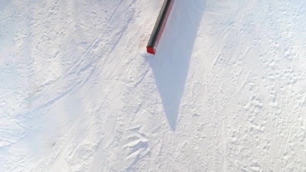 Luchtfoto van snowboarder gedresseerd grind truc op spoor op besneeuwde helling — Stockvideo