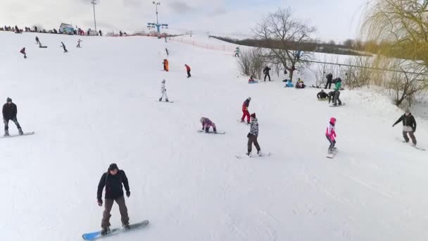 Αεροφωτογραφία του σκιέρ και snowboarders συρόμενη κάτω χιονισμένη πλαγιά και ιππασία με τελεφερίκ — Αρχείο Βίντεο