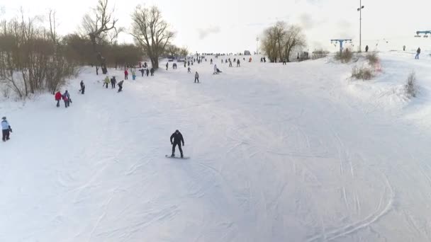 Aerial of snowboarders and skiers sliding down the snowy slope — Stock Video