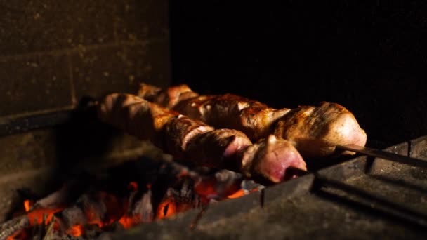 Closeup of skewers with pork meat turning while roasting in wood fired oven — Stock Video