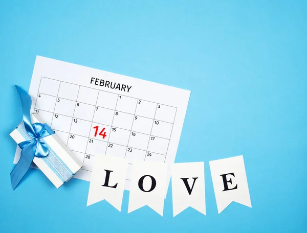 Composizione giorno San Valentino con calendario, confezione regalo, ghirlanda d'amore su sfondo blu con spazio libero — Foto Stock