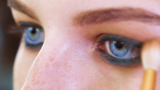Vista de primer plano de cara de mujer joven aplicando sombras de ojos — Vídeos de Stock