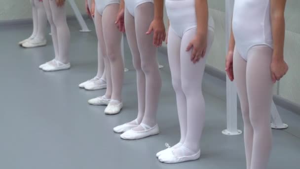 Closeup τα πόδια της λίγο μπαλαρίνες ομάδα στέκεται στην γραμμή άλμα στο στούντιο χορού κλασσικού μπαλέτου — Αρχείο Βίντεο