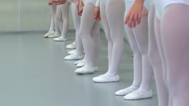 Крупним планом ноги маленької групи балерини в білому взутті в ряд практикують в класичній балетній школі — стокове відео