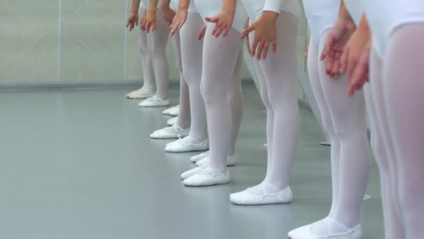 Pernas de close-up de pequeno grupo de bailarinas em sapatos brancos na fileira praticando na escola de balé clássico — Vídeo de Stock