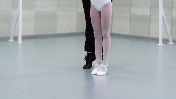 Closeup πόδια της λίγο μπαλαρίνες σε λευκά παπούτσια εξισορρόπησης με δάσκαλο βοηθώντας σε στούντιο μπαλέτου — Αρχείο Βίντεο