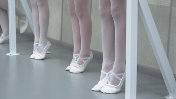 Primer plano piernas de poco grupo de bailarinas en zapatos blancos en fila practicando en la escuela de ballet clásico — Vídeos de Stock