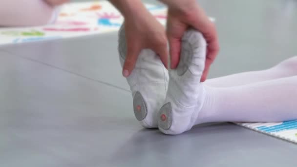 Nahaufnahme Lehrerhände, die kleine Ballerinas in weißen Schuhen in der Balletttanzschule strecken