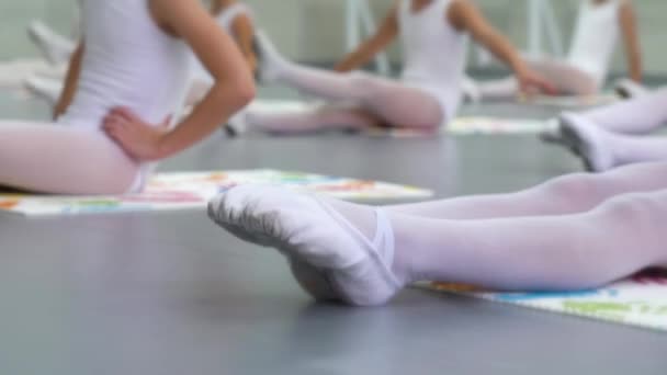 Vértes lábak kis ballerinas csoport fehér cipő gyakorló emeleten balett iskolában — Stock videók