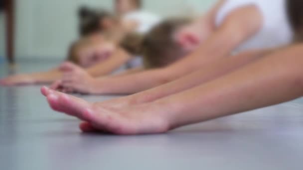 Closeup μικρή μπαλαρίνα που εκτείνεται στο πάτωμα εξάσκηση σε Σχολή Μπαλέτου αργή κίνηση — Αρχείο Βίντεο