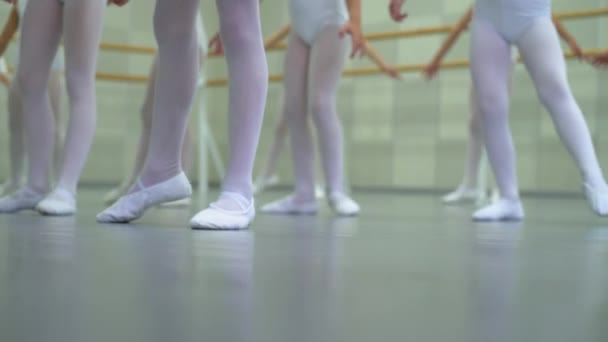 Primer plano piernas de poco grupo de bailarinas en zapatos blancos practicando en el estudio de ballet clásico — Vídeos de Stock