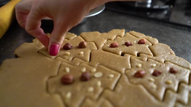 Mujer mano decora galletas crudas cortadas en forma de árbol de Navidad con nueces primer plano — Vídeo de stock