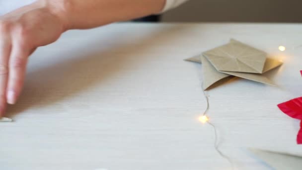 Panning tiro de mãos de mulher dobrando origami estrela de papel para decoração de Natal — Vídeo de Stock