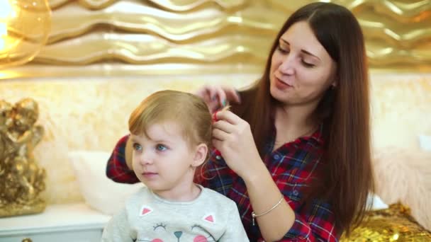 Joven madre hace estilo de pelo para su hija pequeña en casa decorada festiva — Vídeo de stock
