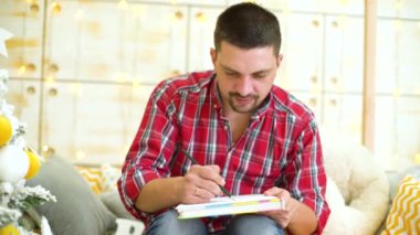 genç evli adam koltukta oturur ve kalemle çizer