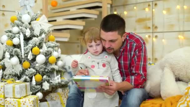 Padre cariñoso enseña a su hija a dibujar en Navidad — Vídeo de stock