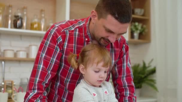 Маленькая девочка и ее отец пекут печенье вместе — стоковое видео