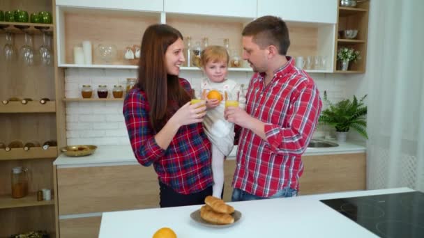 Heureux famille avec tout-petit fille boire du jus d'orange dans la cuisine — Video