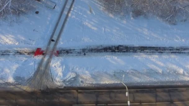 Αεροφωτογραφία του αθλητές τζόκινγκ στο χιονισμένο μονοπάτι κοντά πόλη δρόμο χειμώνα — Αρχείο Βίντεο