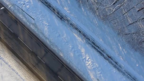 Aerial of people jogging on path near city road in winter — Stock Video